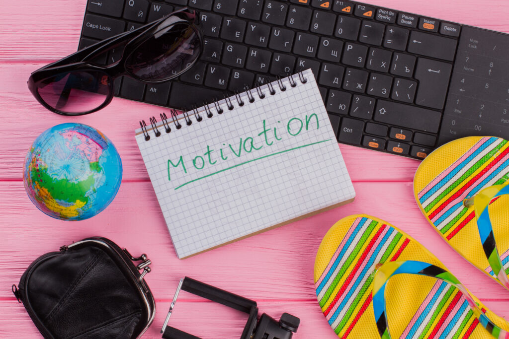Motivation on notebook with woman's traveler accessories.